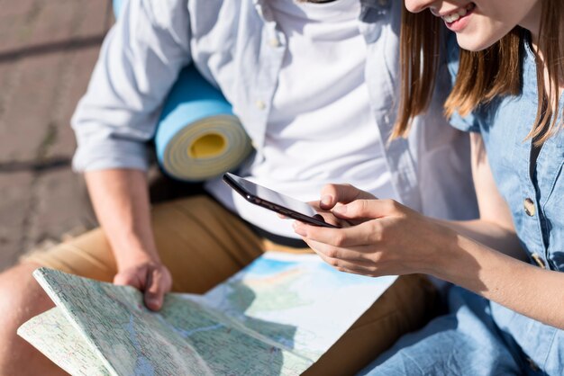Toeristenpaar die telefoon en kaart bekijken
