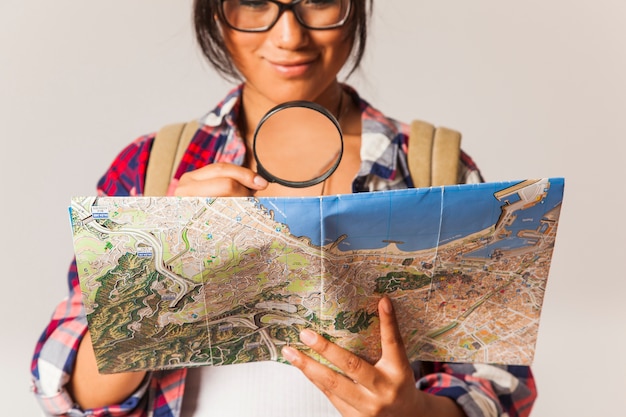 Toeristische vrouw kijkt door vergrootglas op kaart