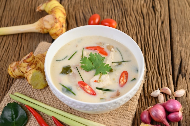 Tom Kha Kai in een kom met kaffir limoenblaadjes, citroengras, rode ui, laos en chilipeper.