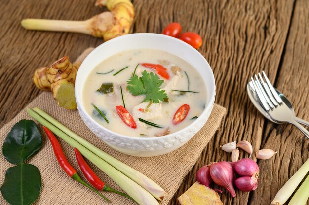 Tom Kha Kai in een kom met kaffir limoenblaadjes, citroengras, rode ui, laos en chilipeper.