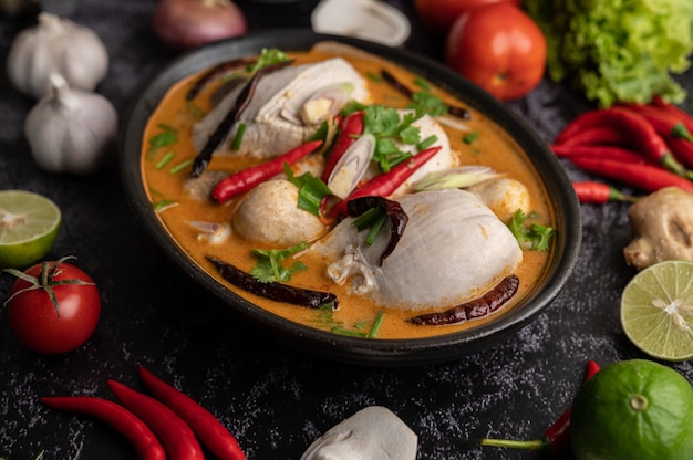 Tom yum kip met chili, koriander, gedroogde chili, kaffir limoenblaadjes, champignons en citroengras in een kom