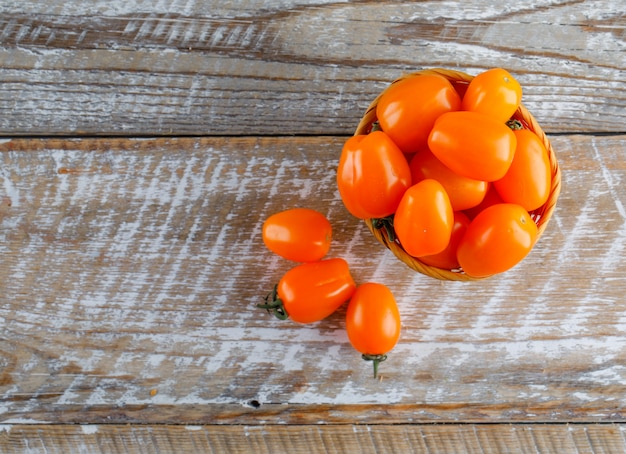 Tomaten in een mand op een houten tafel. plat lag.