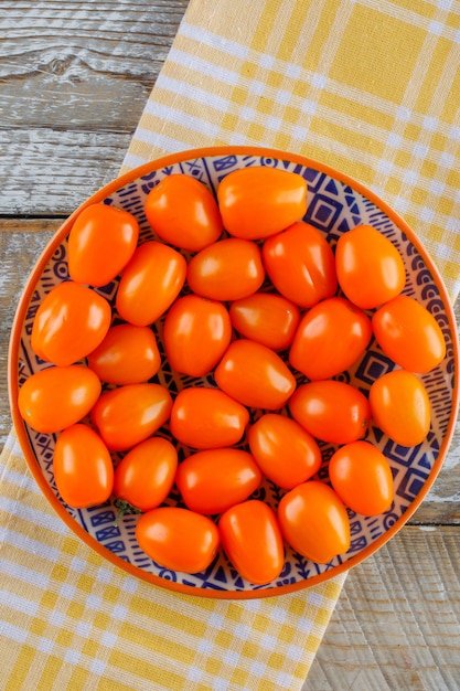 Tomaten in een plaat op houten en keuken handdoek. plat lag.