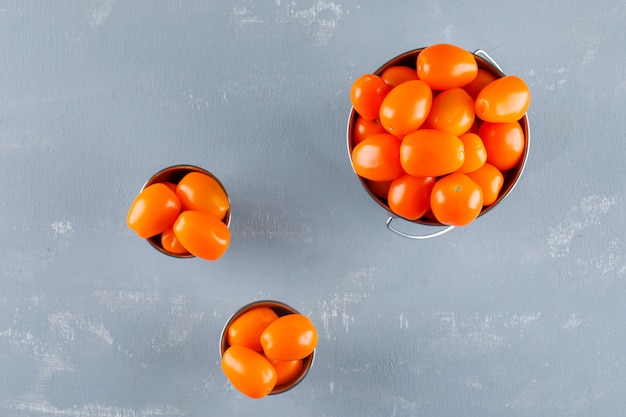 Tomaten in mini-emmers op een gips tafel. plat lag.
