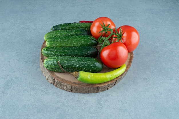 Tomaten, komkommers en peper op houten stuk.