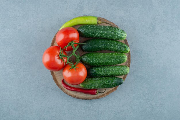 Tomaten, komkommers en peper op houten stuk.