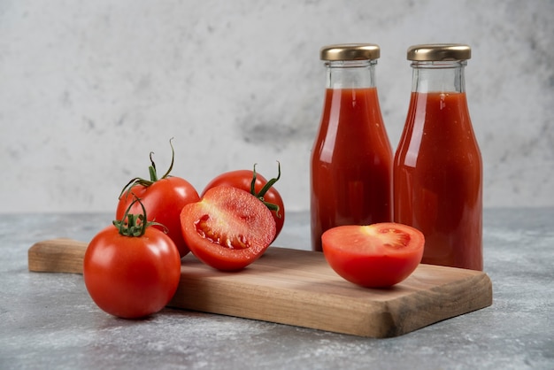 Tomatensap in glazen potten op een houten bord.