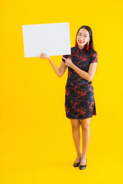 Toont de portret mooie jonge Aziatische vrouwenslijtage Chinese kleding wit leeg aanplakbord