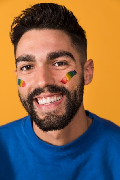 Toothy knappe man met LGBT-symbool op gezicht lacht