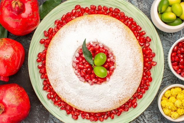 Top close-up cake met granaatappel granaatappel kommen met bessen en een bord cake