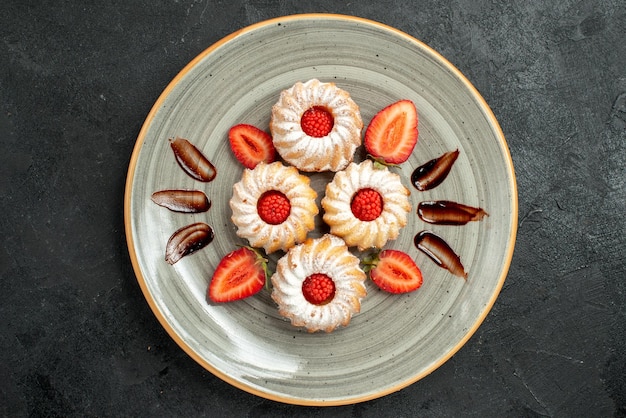 Top close-up cookies met aardbeien smakelijke koekjes met chocolade en aardbei op witte plaat in het midden van de tafel