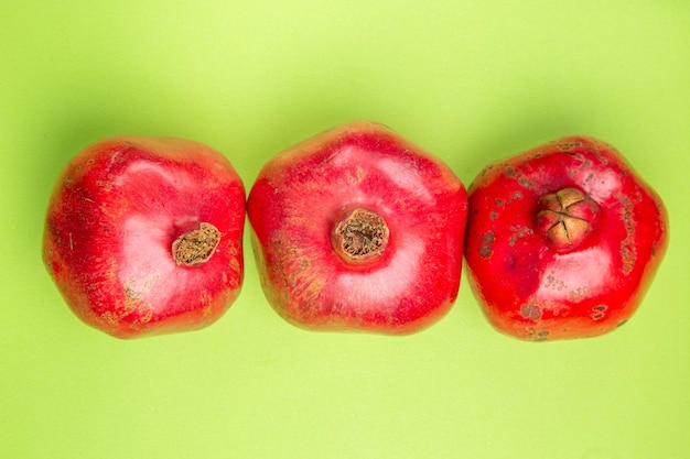 Top close-up weergave fruit drie rijpe smakelijke granaatappels op de groene tafel