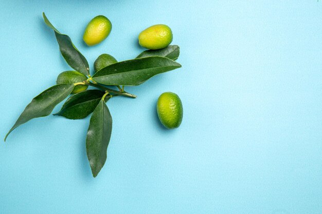 Top close-up weergave fruit groene citrusvruchten met bladeren op de blauwe tafel