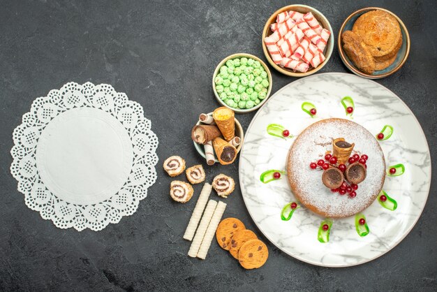 Gratis foto top close-up weergave snoep een cake met rode aalbessen kleurrijke snoepjes wafels kanten kleedje