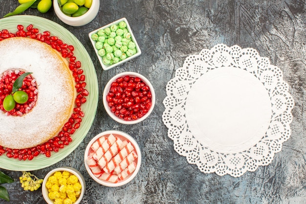 Top close-up weergave snoep kant kleedje het bord cake met citrusvruchten limoenen kleurrijke snoepjes