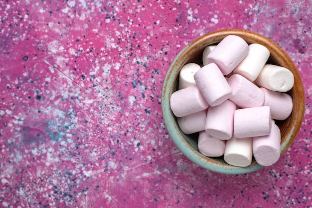 Top dichterbij bekijken zoete heerlijke marshmallows beetje gevormd in ronde pot op roze bureau.