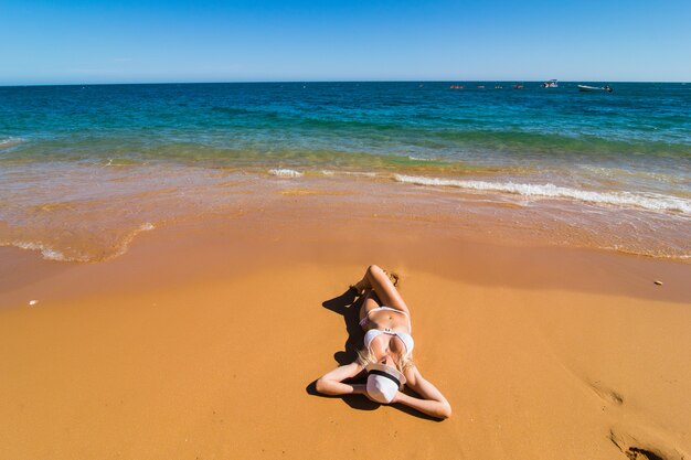 Top luchtfoto drone weergave van vrouw in badpak bikini ontspannen en zonnebaden op het strand