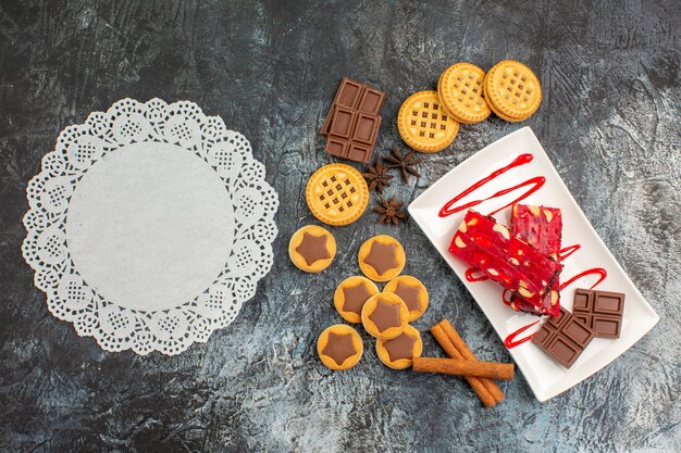 Top phptp van een stuk wit kant met koekjes en een bord geassorteerde chocolade op grijze grond