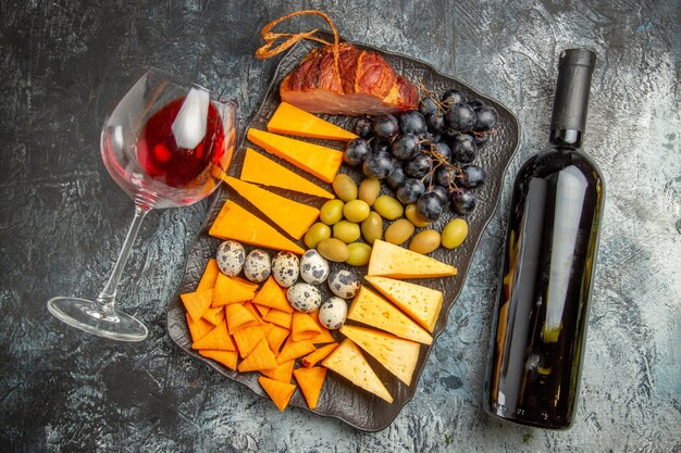 Top van smakelijke beste snack op een bruin dienblad en gevallen wijnglas en fles op ijsachtergrond