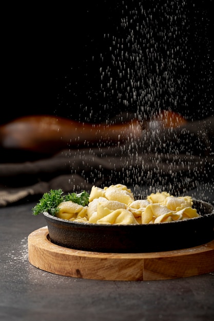 Gratis foto tortellini in donkere metalen plaat op een houten standaard