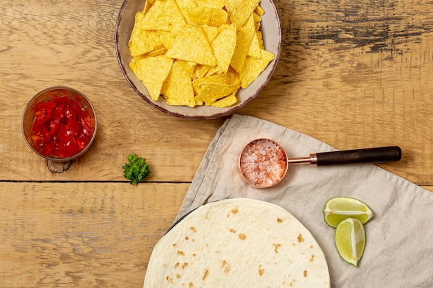 Gratis foto tortilla en nacho's in de buurt van tomaten, roze zout en gesneden limoen