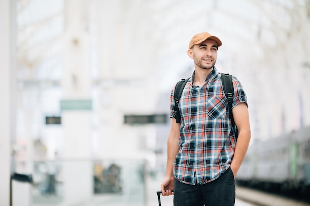 Gratis foto tourist man backpacker en koffer om te reizen op treinstation