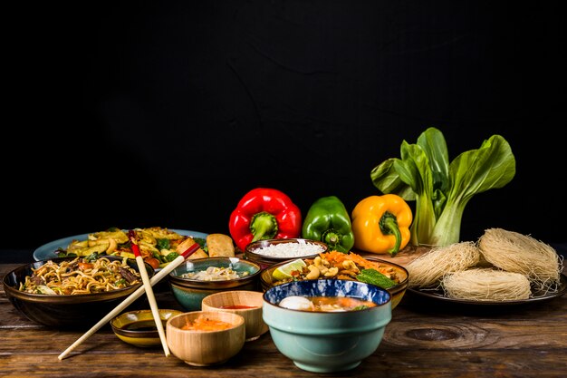 Traditioneel Thais eten met rijstvermicelli; groene paprika&#39;s en bokchoy op bureau tegen zwarte achtergrond