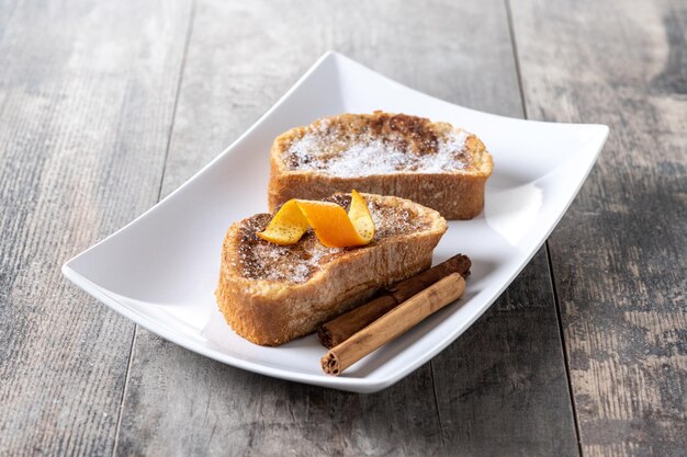 Traditionele huisgemaakte Spaanse torrijas versierd met kaneel en sinaasappelschil op houten tafel