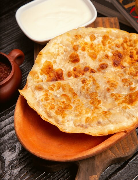 Traditionele Kaukasische gutab, kutab, gozleme met sumakh en yoghurt in houten plaat.