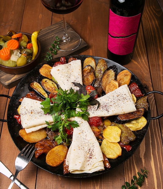 Traditionele Kaukasische zakje ici met gebakken kip, aubergine, aardappelen, tomaten, courgette en geserveerd met lavash, peterselie, turshu.