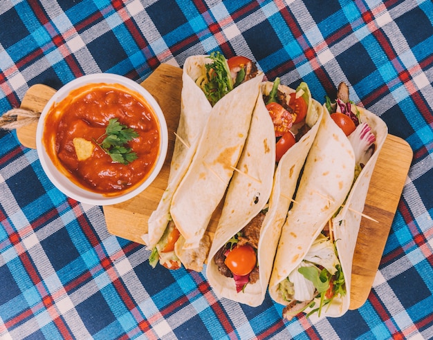 Gratis foto traditionele mexicaanse taco's; salsa saus met vlees en groenten op snijplank