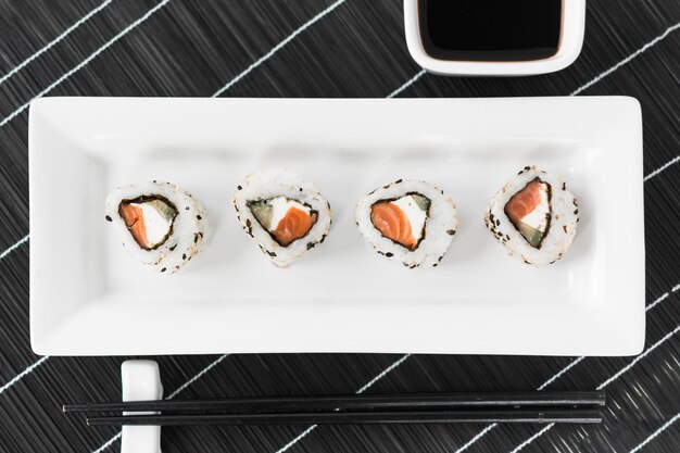 Traditionele smakelijke sushi in wit dienblad met saus en eetstokjes
