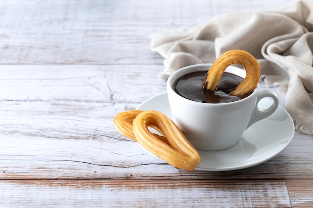 Gratis foto traditionele spaanse churros met warme chocolademelk ontbijt op houten tafel