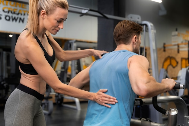 Trainer helpt beginner in de sportschool