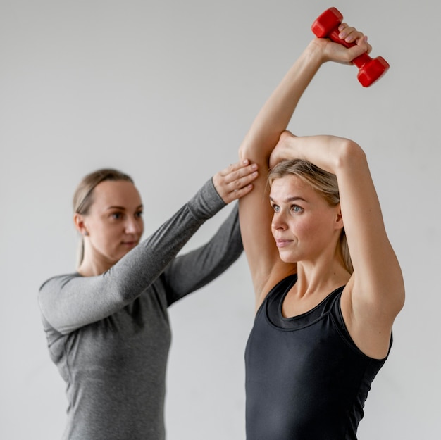 Training met personal trainer en dumbbells medium shot