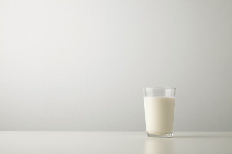 Gratis Foto transparant glas met verse biologische melk geïsoleerd aan de zijkant van de witte tafel. ruimte voor uw tekst hierboven