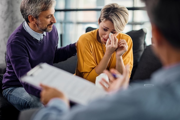 Treurige vrouw huilt terwijl ze met haar man in therapie is met counselor