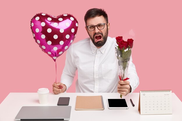 Triest boos man ontvangt weigering van collega tot nu toe, draagt boeket rozen, Valentijn, huilt van wanhoop, gekleed in elegant wit overhemd