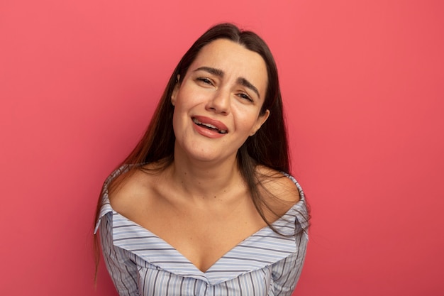 Triest mooie vrouw kijkt naar voorzijde geïsoleerd op roze muur