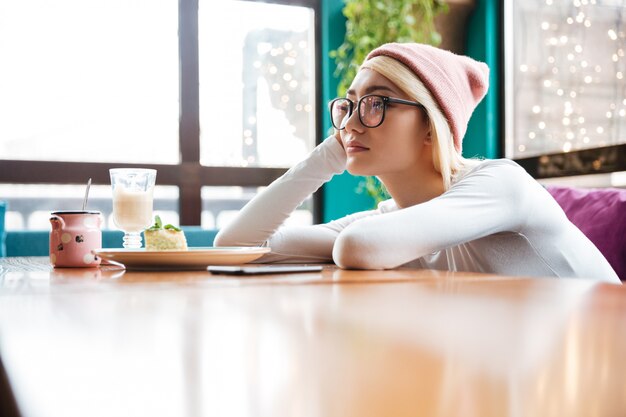 Triest verveeld jonge vrouw zitten aan de tafel in café