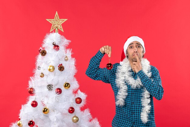 Trieste jonge man met kerstman hoed in een blauw gestreept shirt en decoratie-accessoire te houden