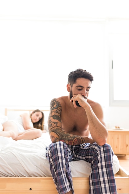 Trieste jonge man zittend op bed voor zijn vriendin