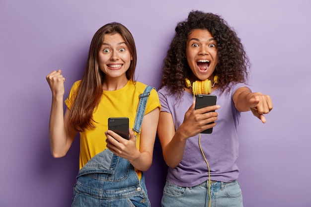 Triomfantelijke vriendinnen poseren met hun telefoons