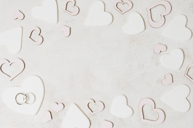 Gratis foto trouwringen op witte hartvorm over de concrete achtergrond
