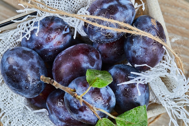 Gratis foto tuin pruimen in een mand op houten tafel, close-up.