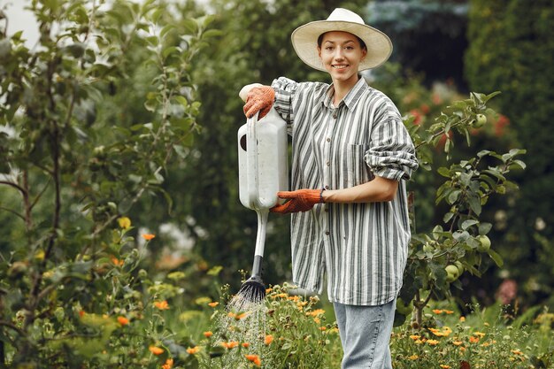 Tuinieren in de zomer. vrouw bloemen met een gieter water geven. meisje met een hoed.