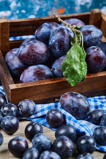 Gratis foto tuinpruimen verspreid door houten tafel.