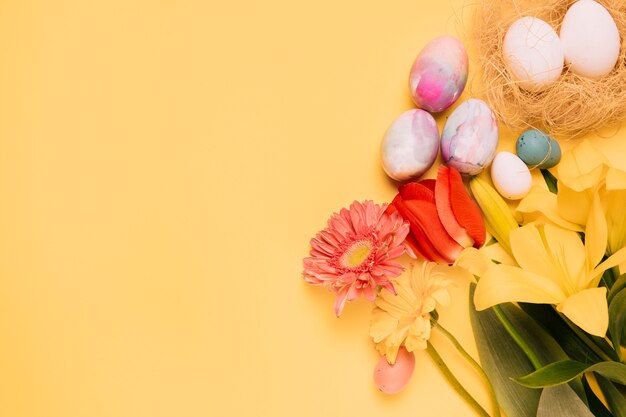 Tulp; gerbera en lelie bloemen met paaseieren op gele achtergrond