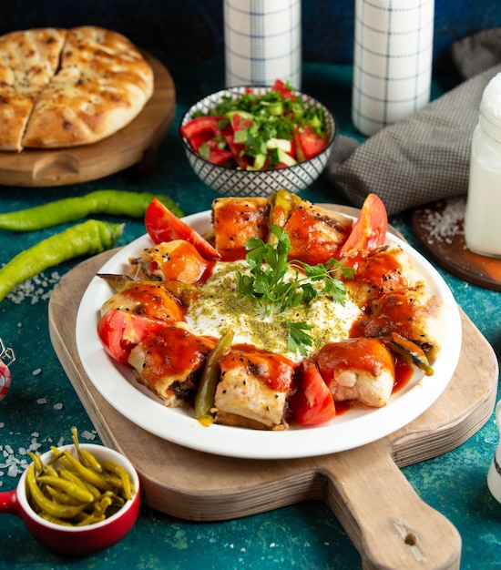 Turkse schotel beyti kebab met rundvlees gewikkeld in flatbread geserveerd met tomatensaus