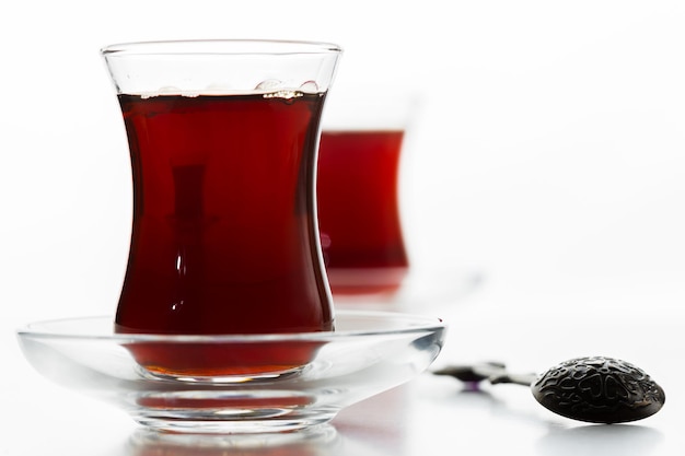 Turkse thee in traditioneel glas dat op witte achtergrond wordt geïsoleerd Premium Foto